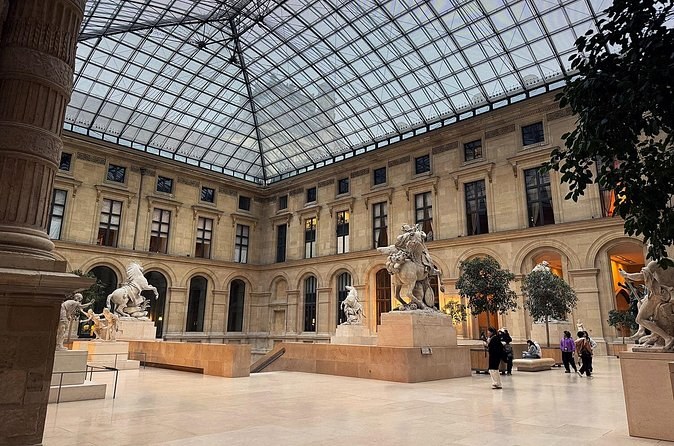 A glass-roofed courtyard of French garden sculpture, rearing horses in the centre