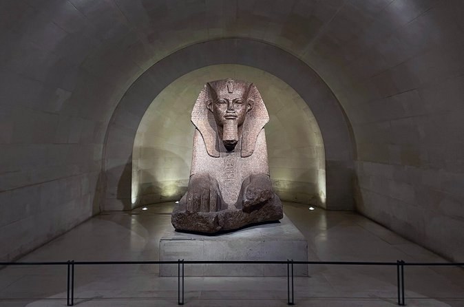 A granite sphinx lit in a vaulted stone crypt