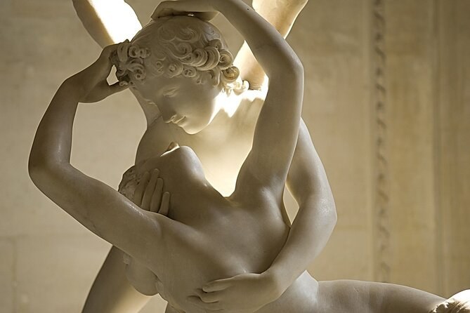 A white marble sculpture of two winged lovers in an embrace