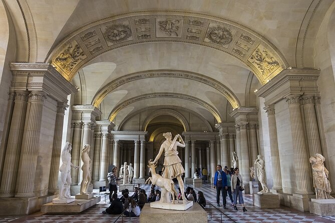 A vaulted hall of ancient marble statues under a painted ceiling